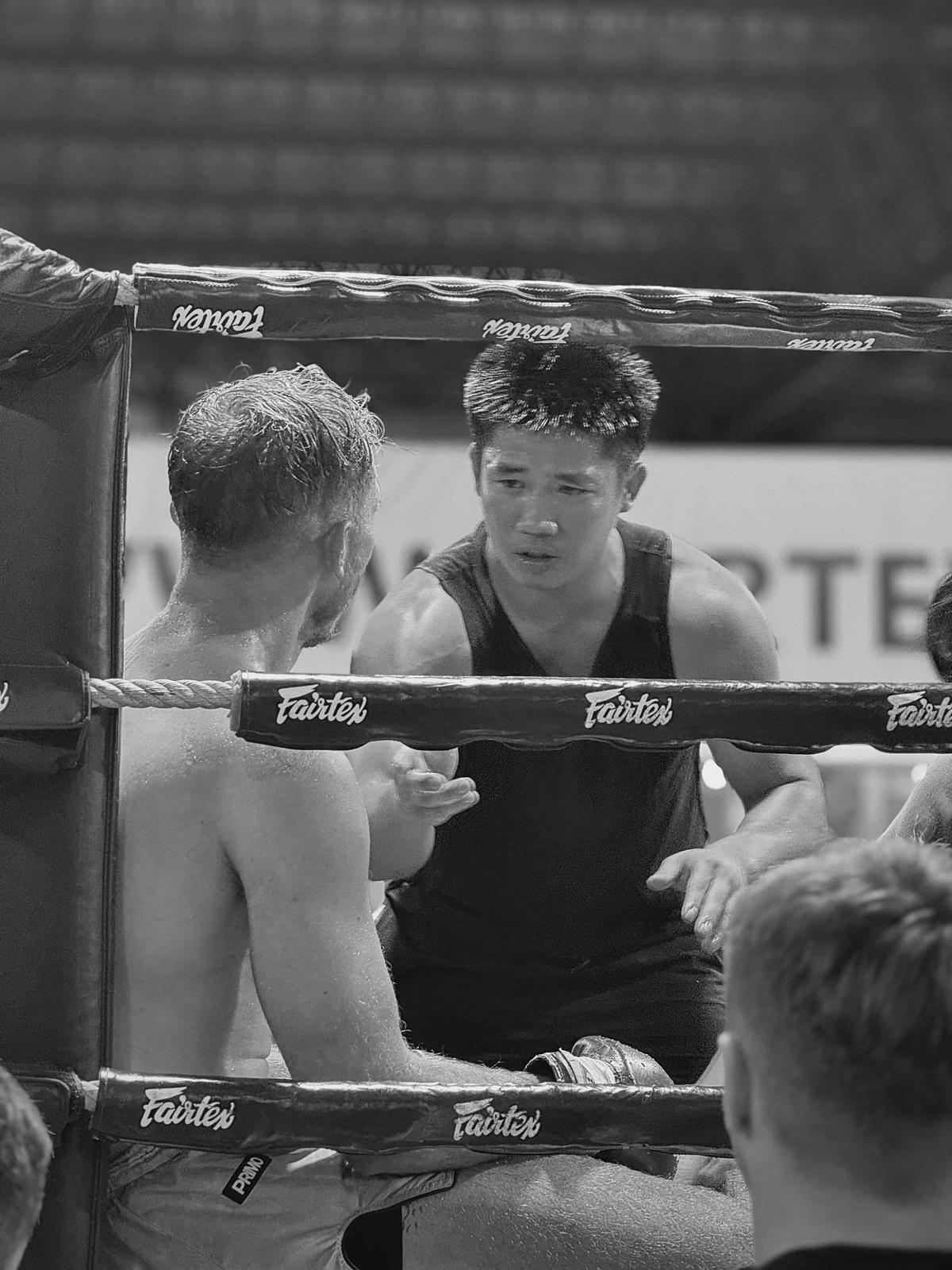 Muay Thai coach giving advice to a fighter in the ring corner
